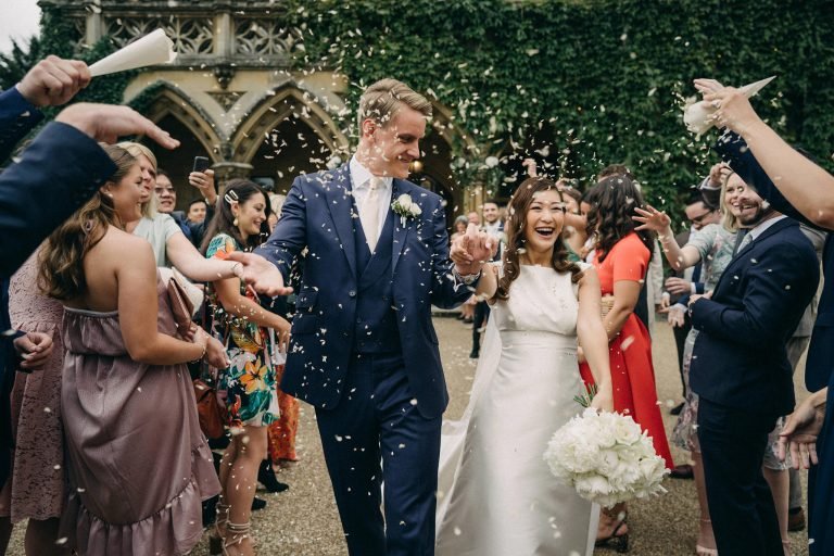 a wedding in cheltenham UK with couple marching out with their friends celebrating by singapore wedding photographer