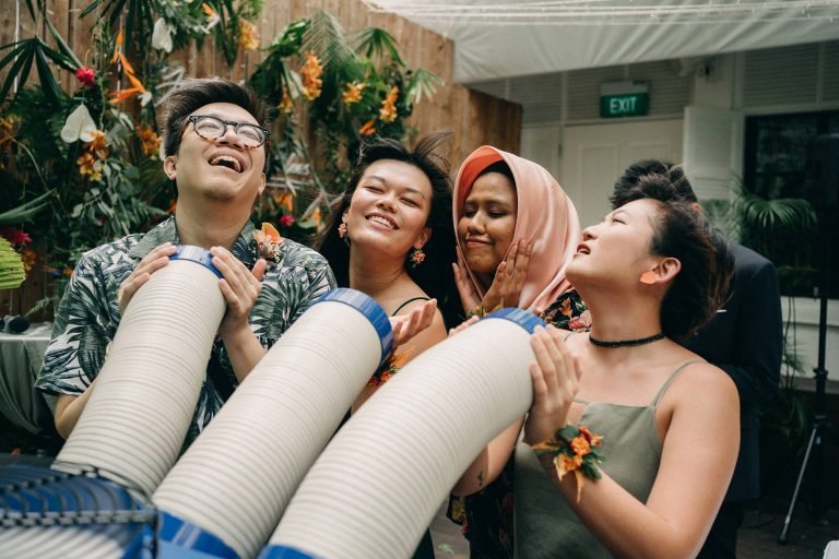 Joyful wedding guests at a botanical garden in Singapore, holding party poppers.