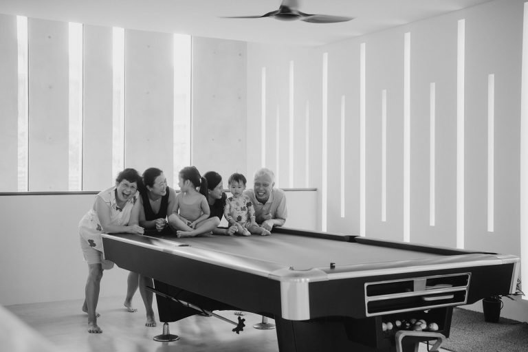 Family having a moment on pool table during photography session with Singapore family photographer
