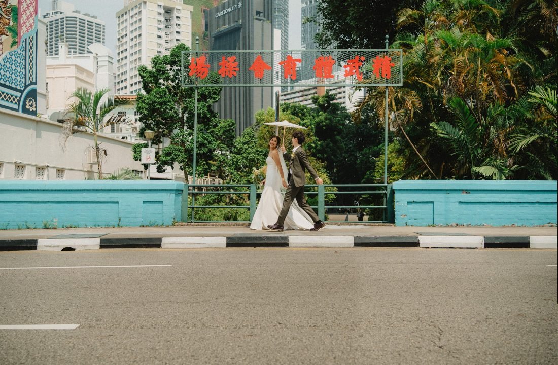 Bride and groom under umbrella near red Chinese sign, Tamarind Hill wedding photography
