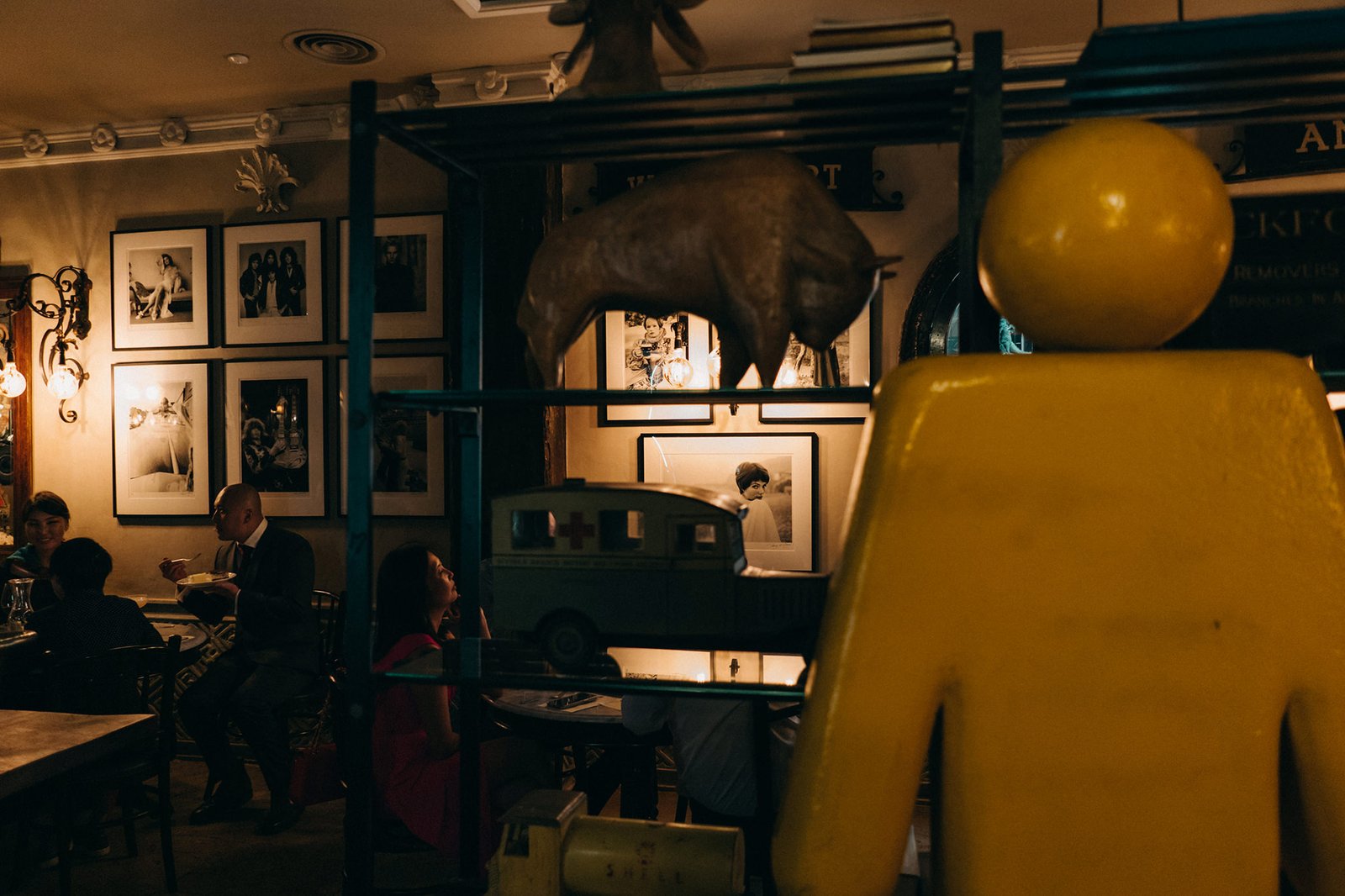 Warmly lit interior of The English House wedding venue in Singapore, with guests dining at tables and framed photos adorning the walls, evoking a vintage, intimate atmosphere.