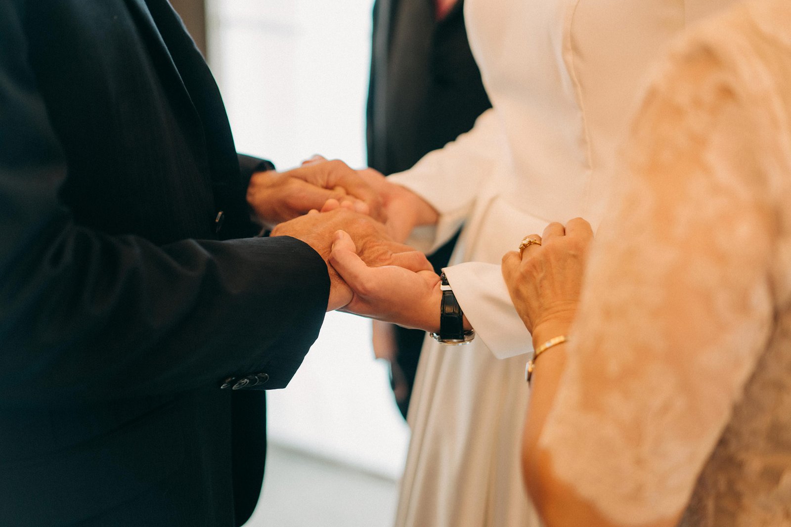 Close-up of hands being joined during a wedding ceremony at the Keyaki Garden Pavilion in Singapore, symbolizing union and commitment.