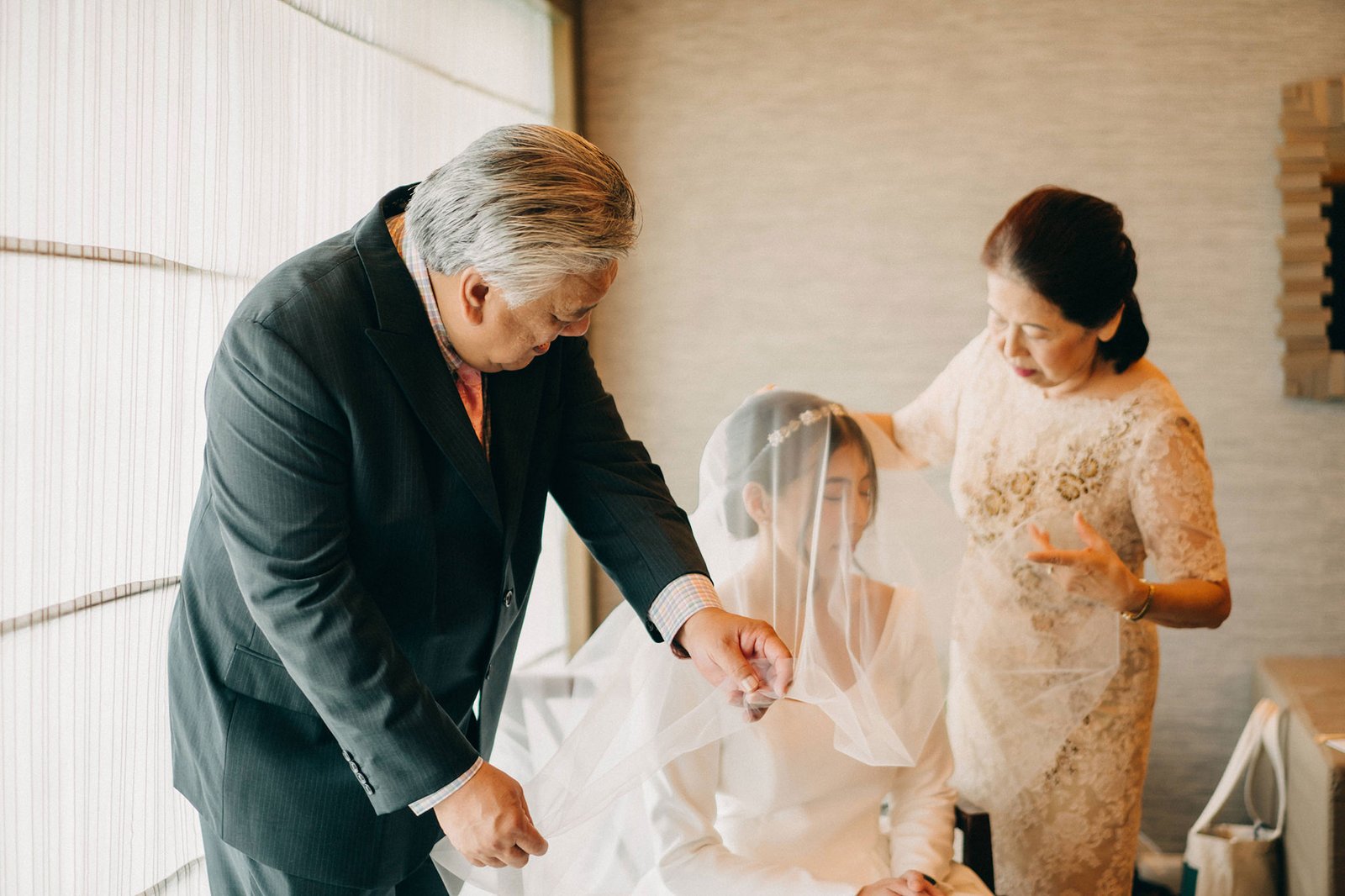 Bride's parents lovingly place her veil during a Keyaki Garden Pavilion wedding in Singapore, capturing a tender moment of family tradition and joy.