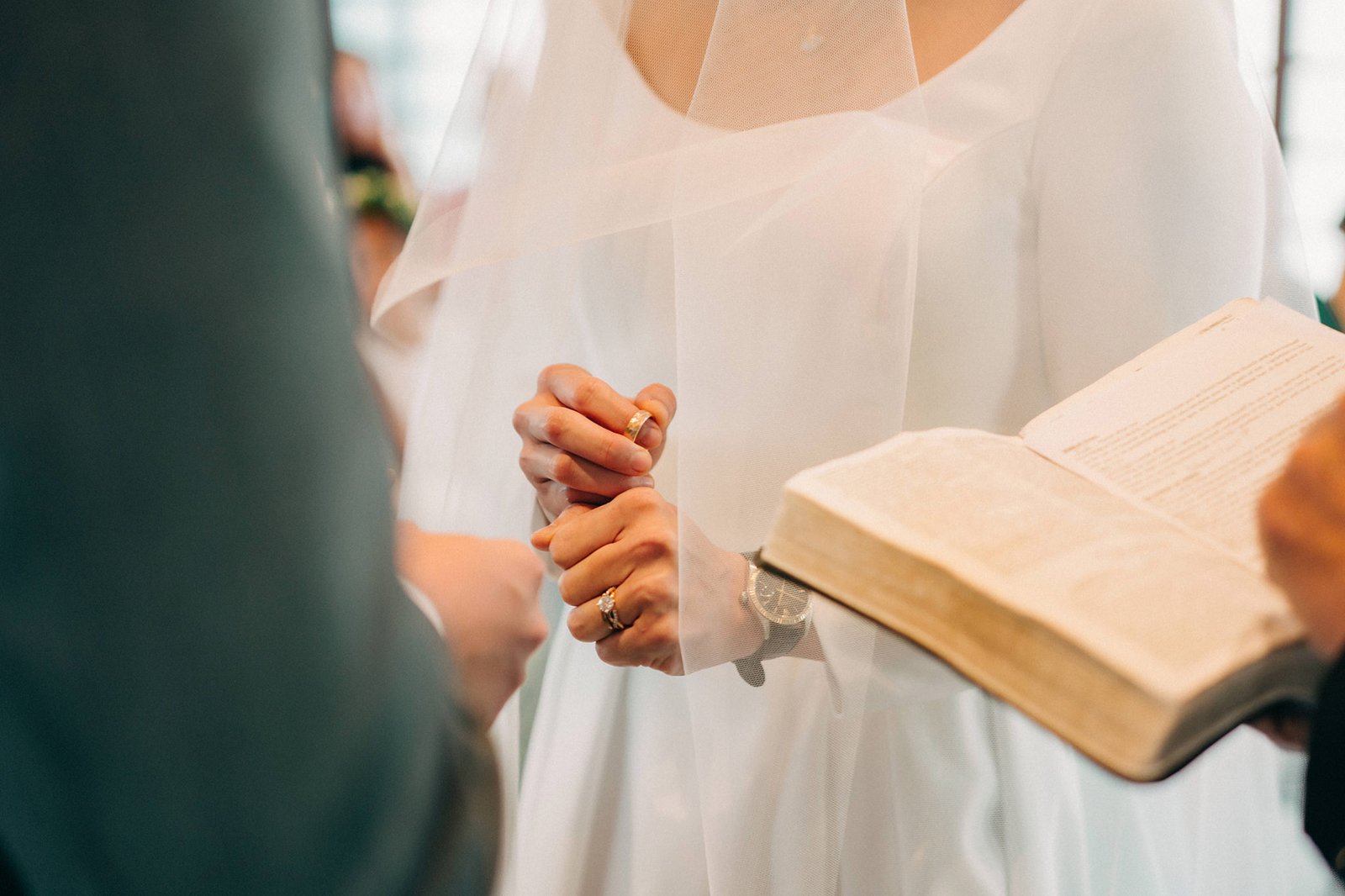 Bride and groom exchanging rings during a wedding ceremony at the Keyaki Garden Pavilion in Singapore, with a bible open beside them.