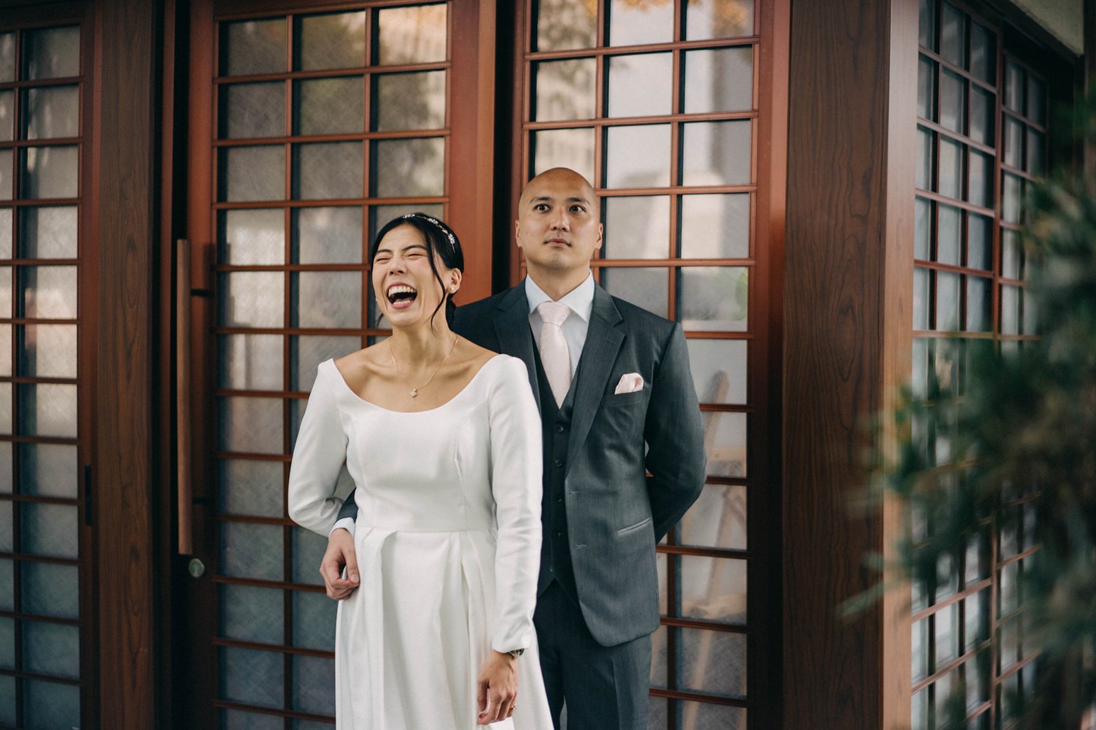 Bride laughs joyfully in a white wedding dress next to groom in suit at Keyaki Garden Pavilion Wedding Singapore.