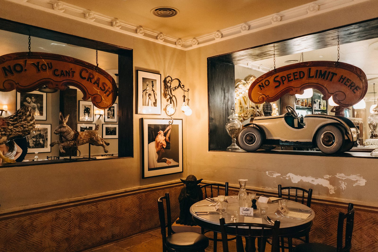 Interior of a whimsical restaurant, possibly at The English House Wedding Singapore, with quirky decor including vintage car and rabbit sculptures, and signs reading "NO. YOU CAN'T CRASH" and "NO SPEED LIMIT HERE.