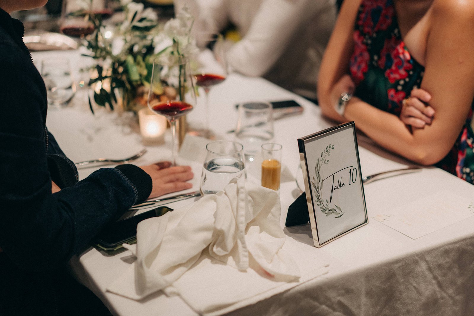 A table setting at a wedding reception at Monti at 1-Pavilion in Singapore, with a "Table 10" sign, wine glasses, and floral arrangements. Wedding photography by [Your Photography Business Name].