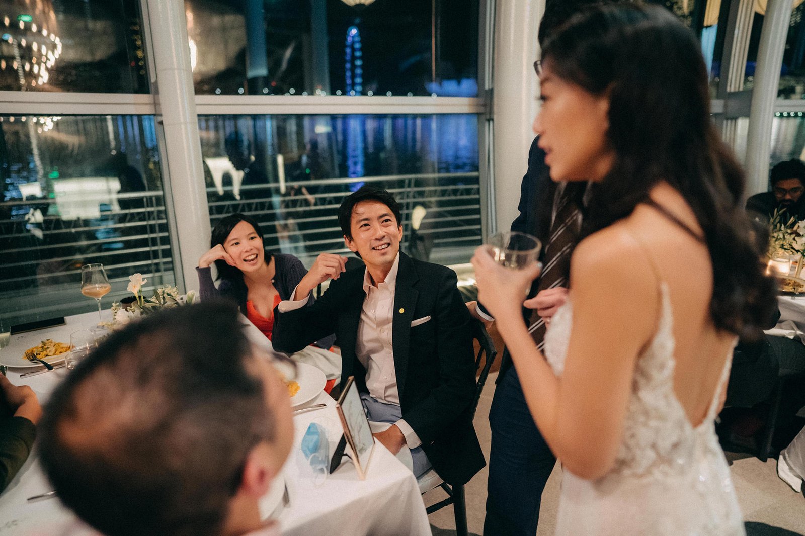 A happy Asian couple celebrates at a wedding reception at Monti at 1-Pavilion, Singapore, with city lights in the background.