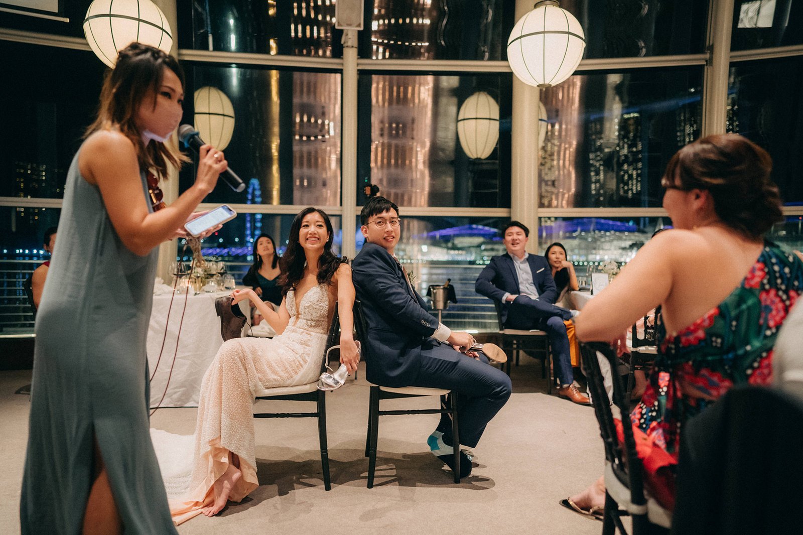 Bride and groom seated, listening to a speech at a monti at 1-pavilion wedding in Singapore