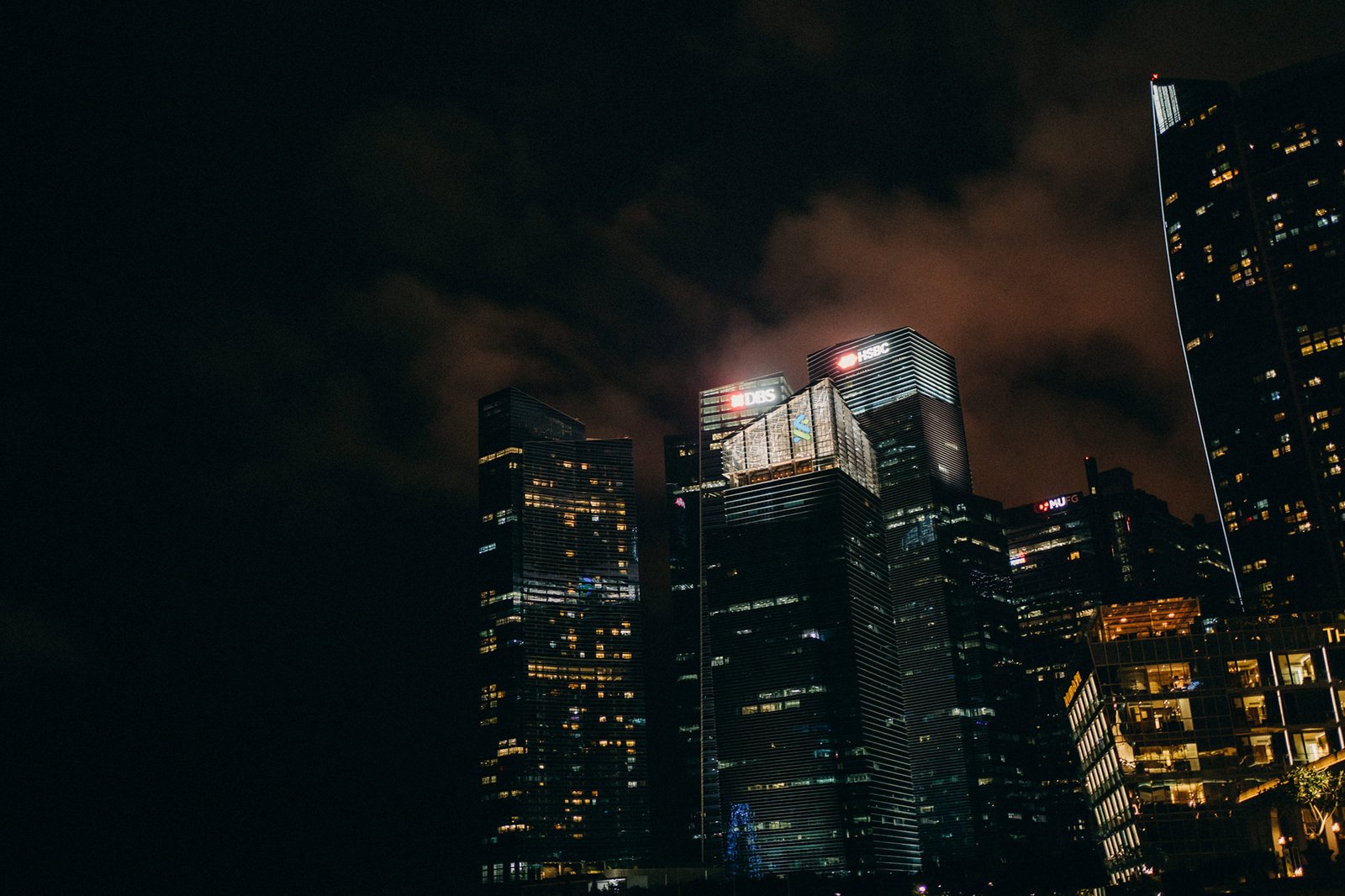 Nighttime view of the Monti at 1-Pavilion wedding venue in Singapore, with illuminated skyscrapers and cloudy skies.