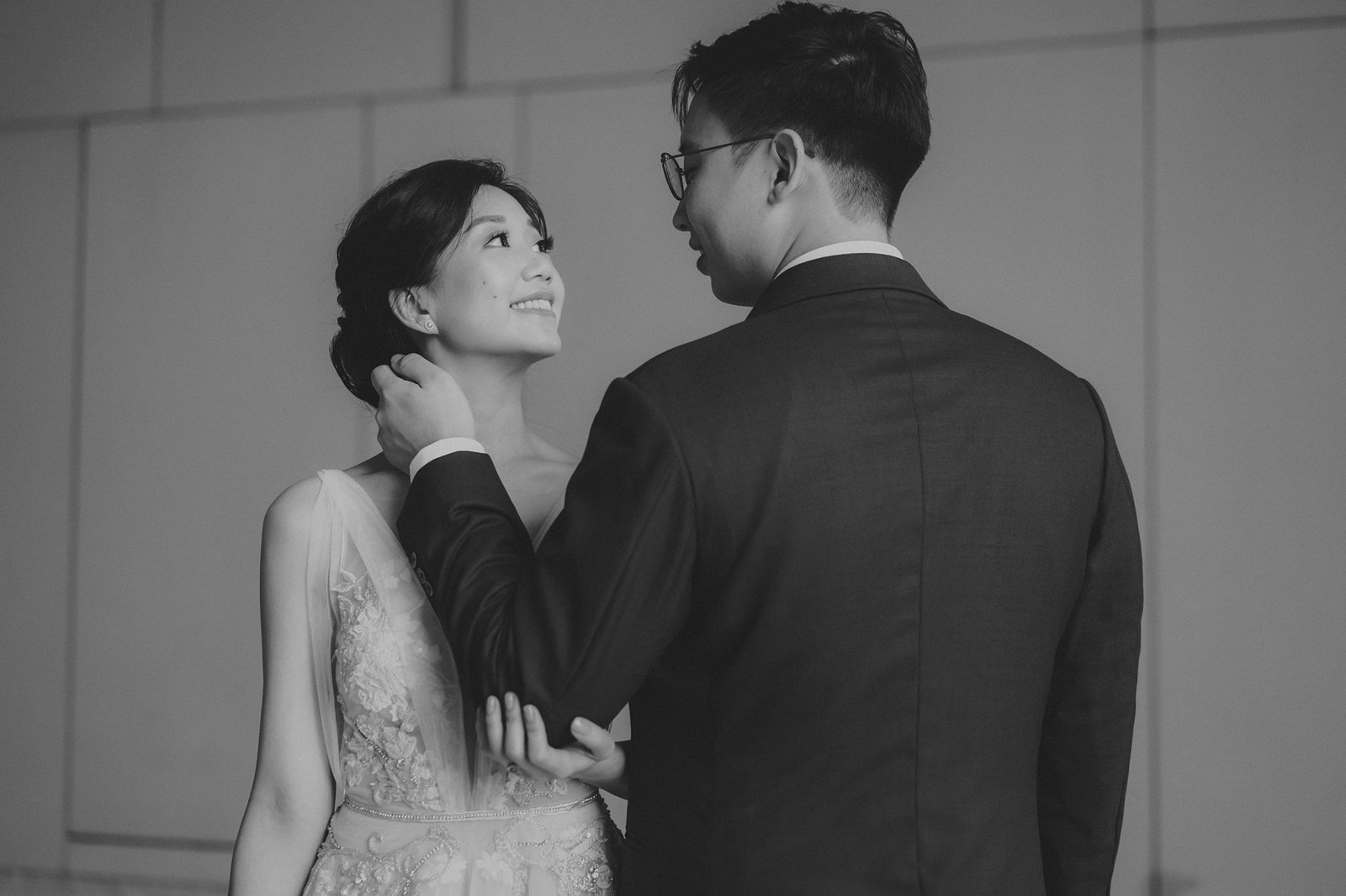 A bride in a delicate gown and groom in a suit share a tender moment at a Monti at 1-Pavilion wedding in Singapore, captured by photography.