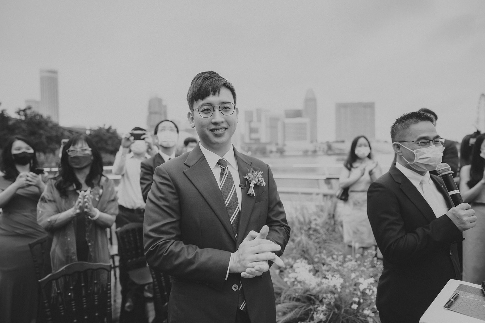 Groom in a suit smiles at a wedding ceremony at Monti at 1-Pavilion, Singapore, with guests in the background. Monti at 1-Pavilion wedding Singapore photography.