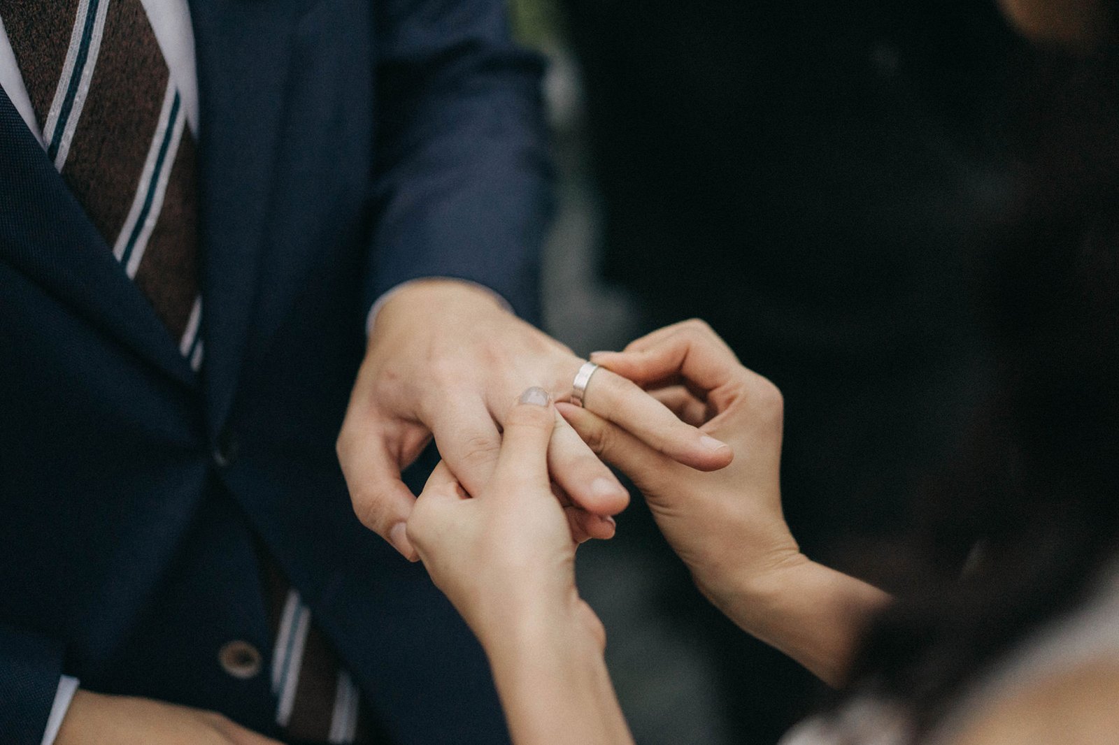 Bride places a wedding ring on groom's finger during a Monti Circles ceremony at 1-Pavilion, Singapore, captured by wedding photography.