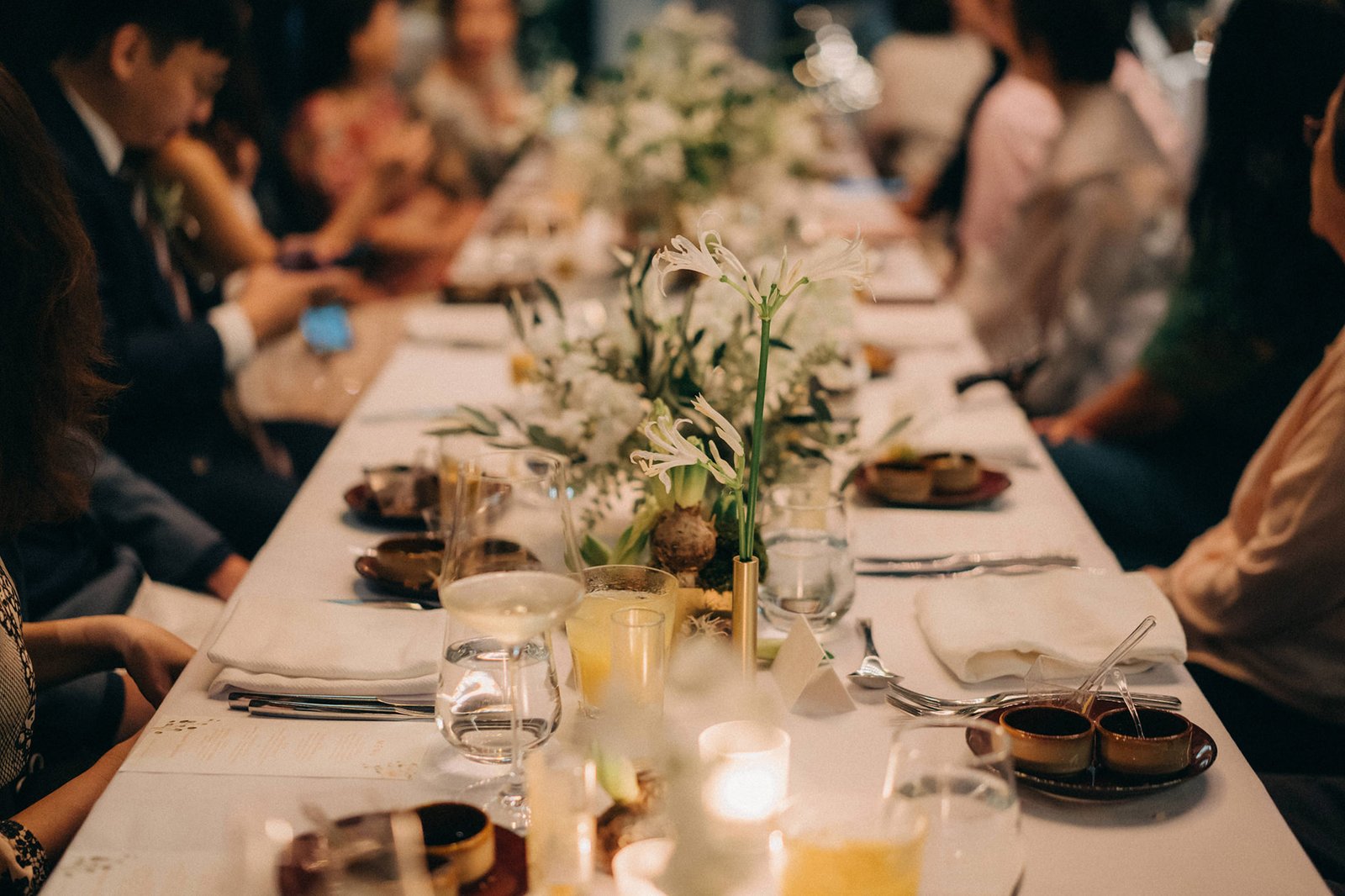 A beautifully set long dining table at a Monti at 1-Pavilion wedding in Singapore, adorned with white floral arrangements and soft lighting, ready for a celebratory dinner.