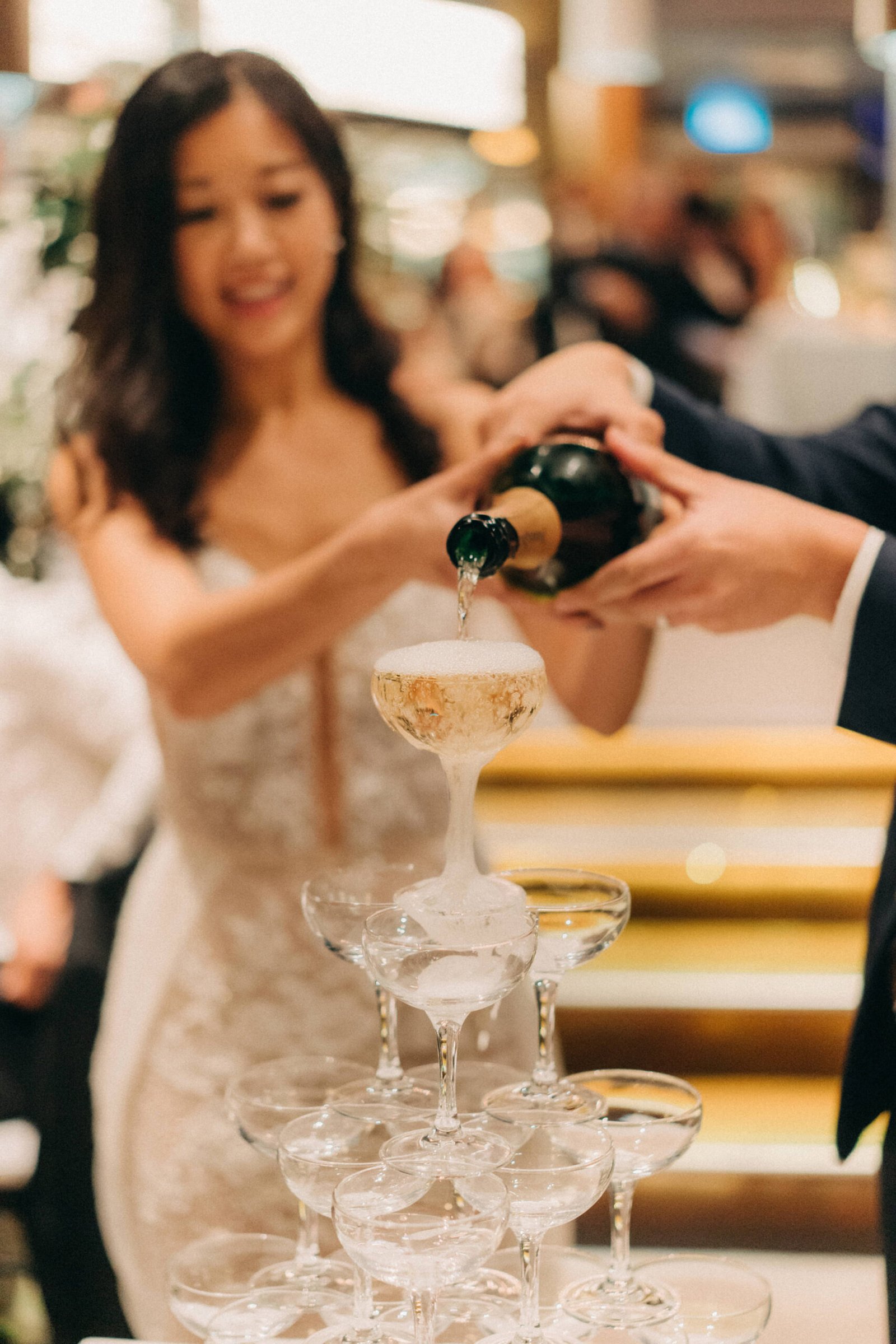 Bride and groom pouring champagne into a tower at their Monti at 1-Pavilion wedding in Singapore, captured by wedding photography.