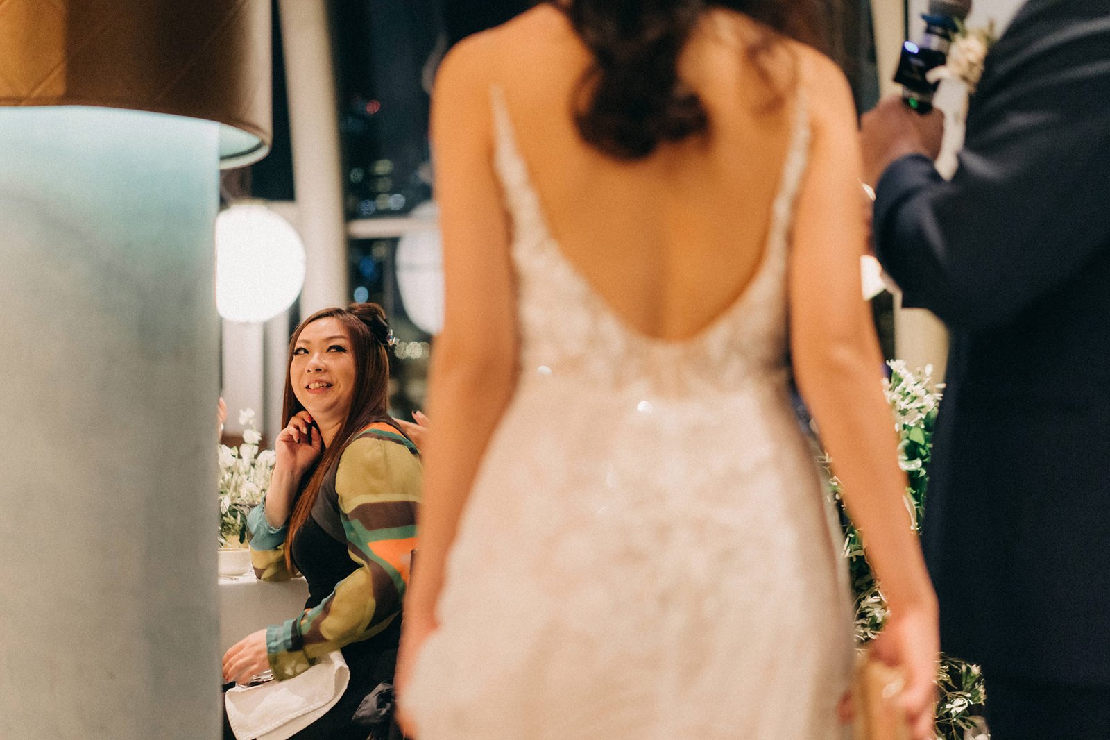 A woman in a white wedding dress smiles as she looks towards a woman in a colorful jacket at a Monti at 1-Pavilion wedding in Singapore, captured by wedding photography.