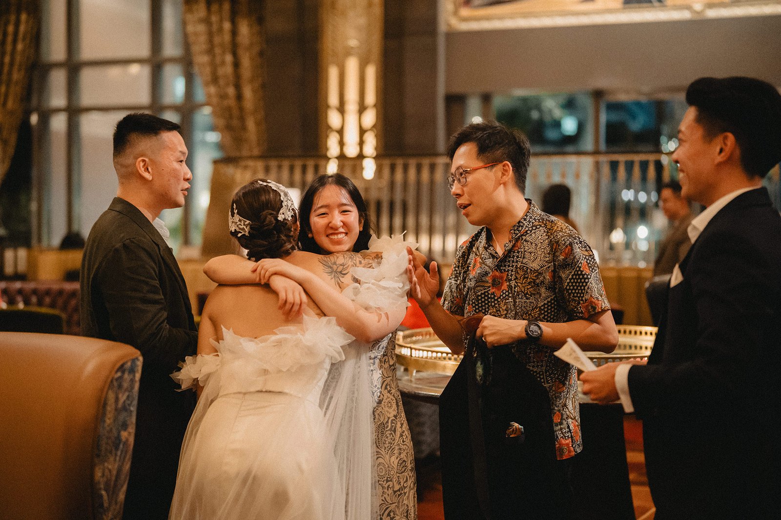 Jared and Xinyu's wedding at Atlas Bar Singapore: bride hugs friend.