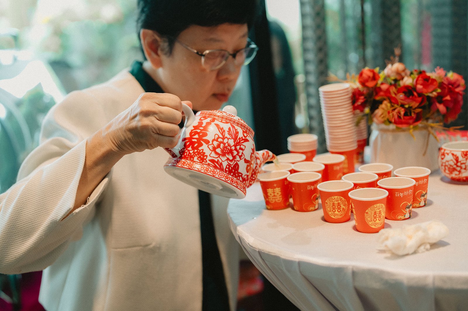 Traditional Chinese tea ceremony at Atlas Bar Singapore wedding with red floral decor.