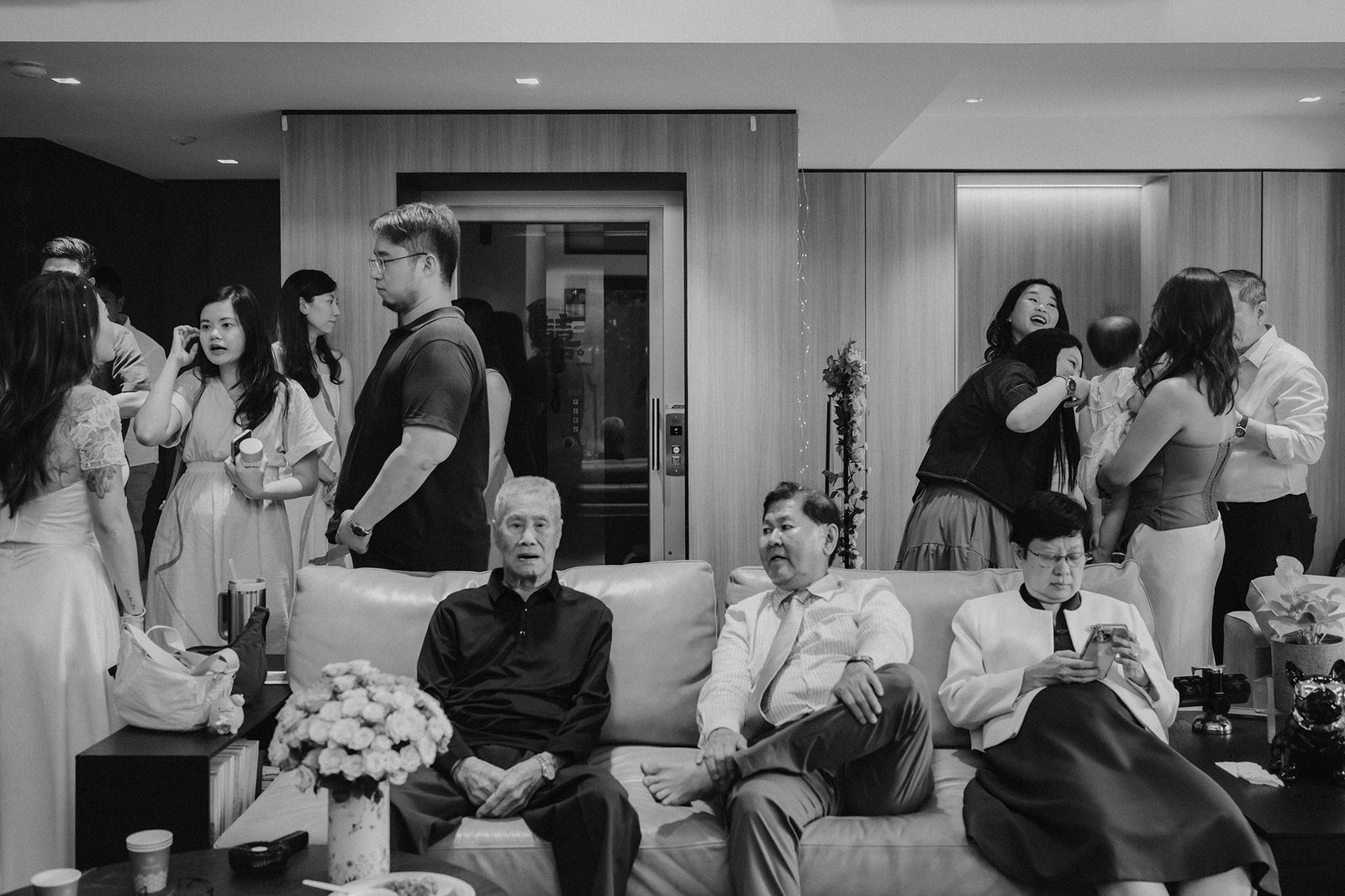 Wedding guests at Atlas Bar Singapore, including older men on a couch and younger people mingling.