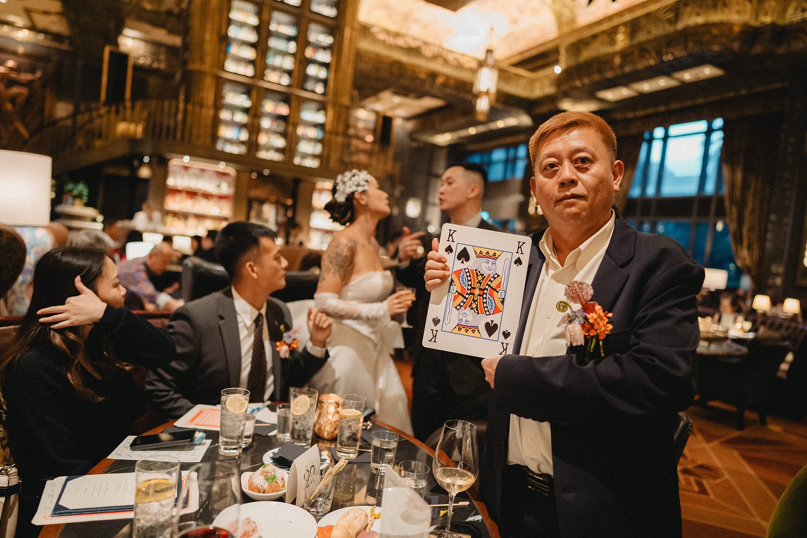 Man holds up a king of spades card at an Atlas Bar Singapore wedding reception.