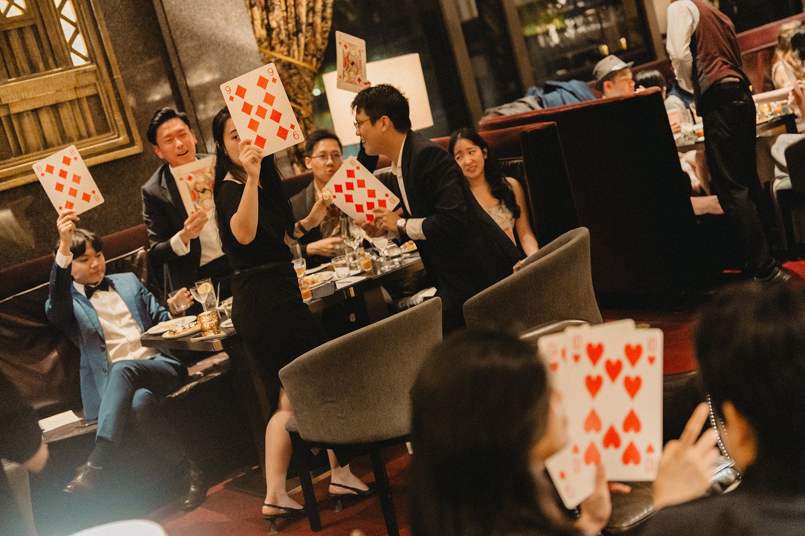 Jared and Xinyu's wedding at Atlas Bar Singapore: guests play cards.