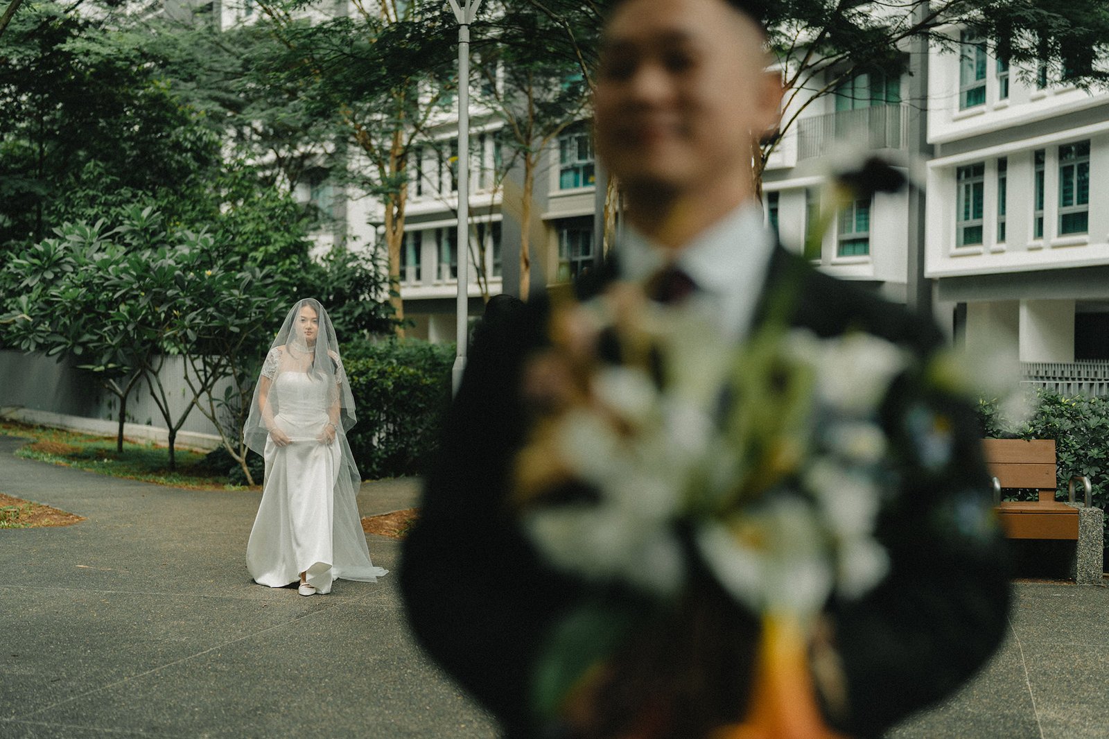 Bride in veil walks toward groom holding bouquet at Atlas bar Singapore wedding.