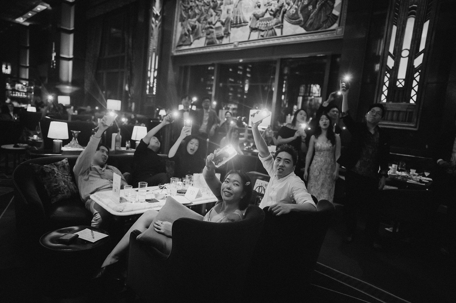 Jared + Xinyu's wedding celebration at Atlas Bar Singapore, guests holding lights.