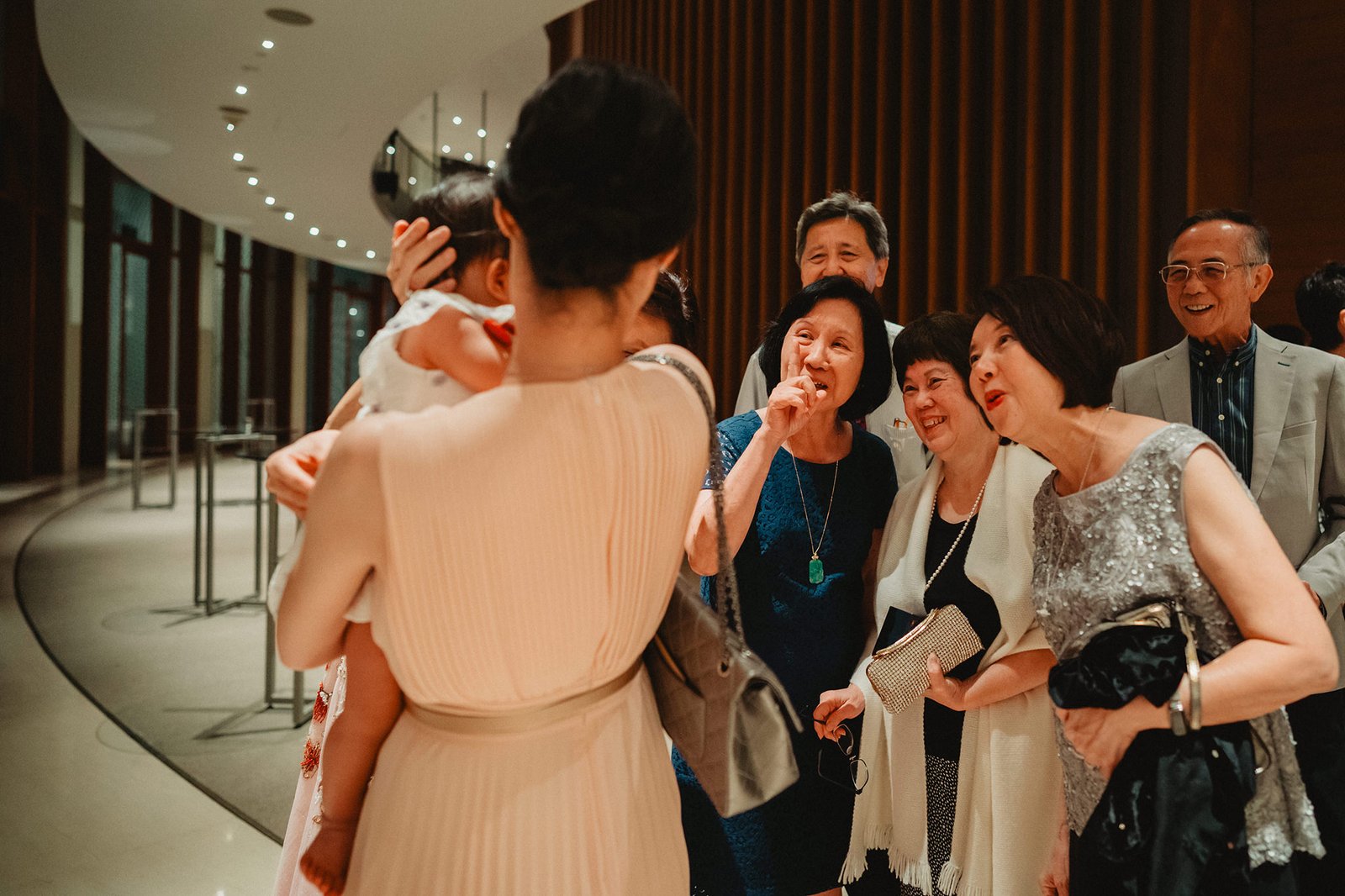 Family celebrates at a Capella Singapore wedding, with a woman holding a baby.