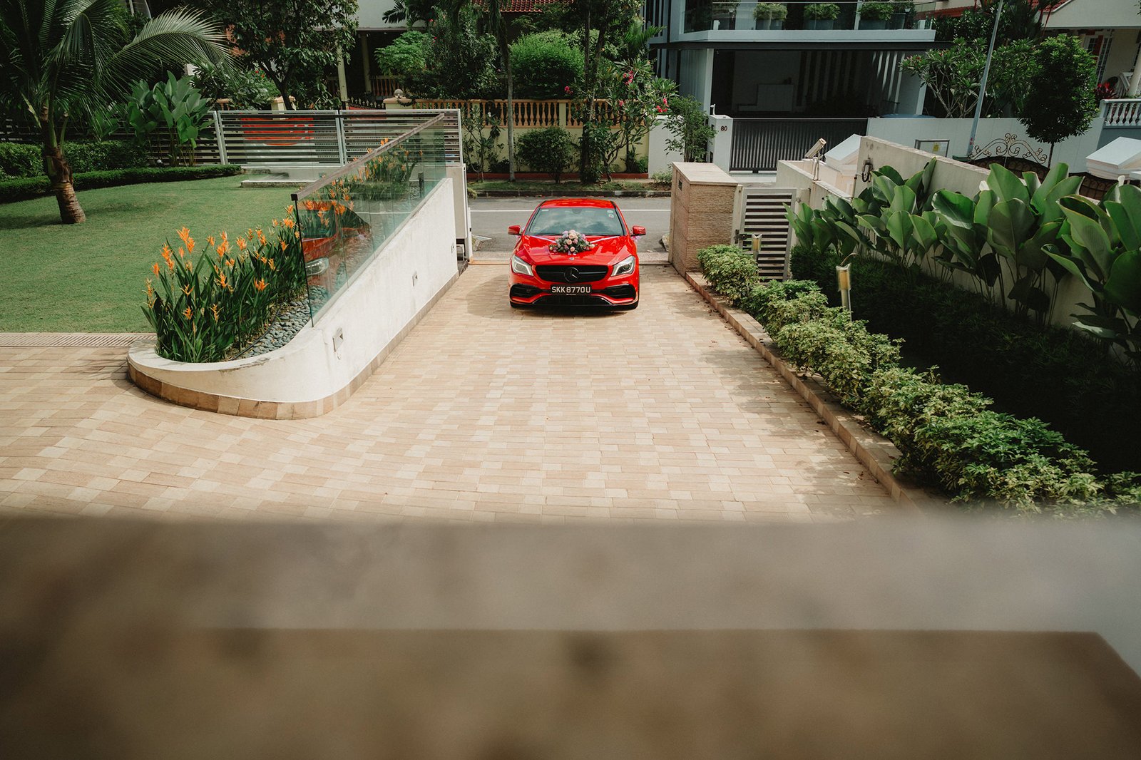 Red wedding car with floral arrangement parked at Capella Singapore.