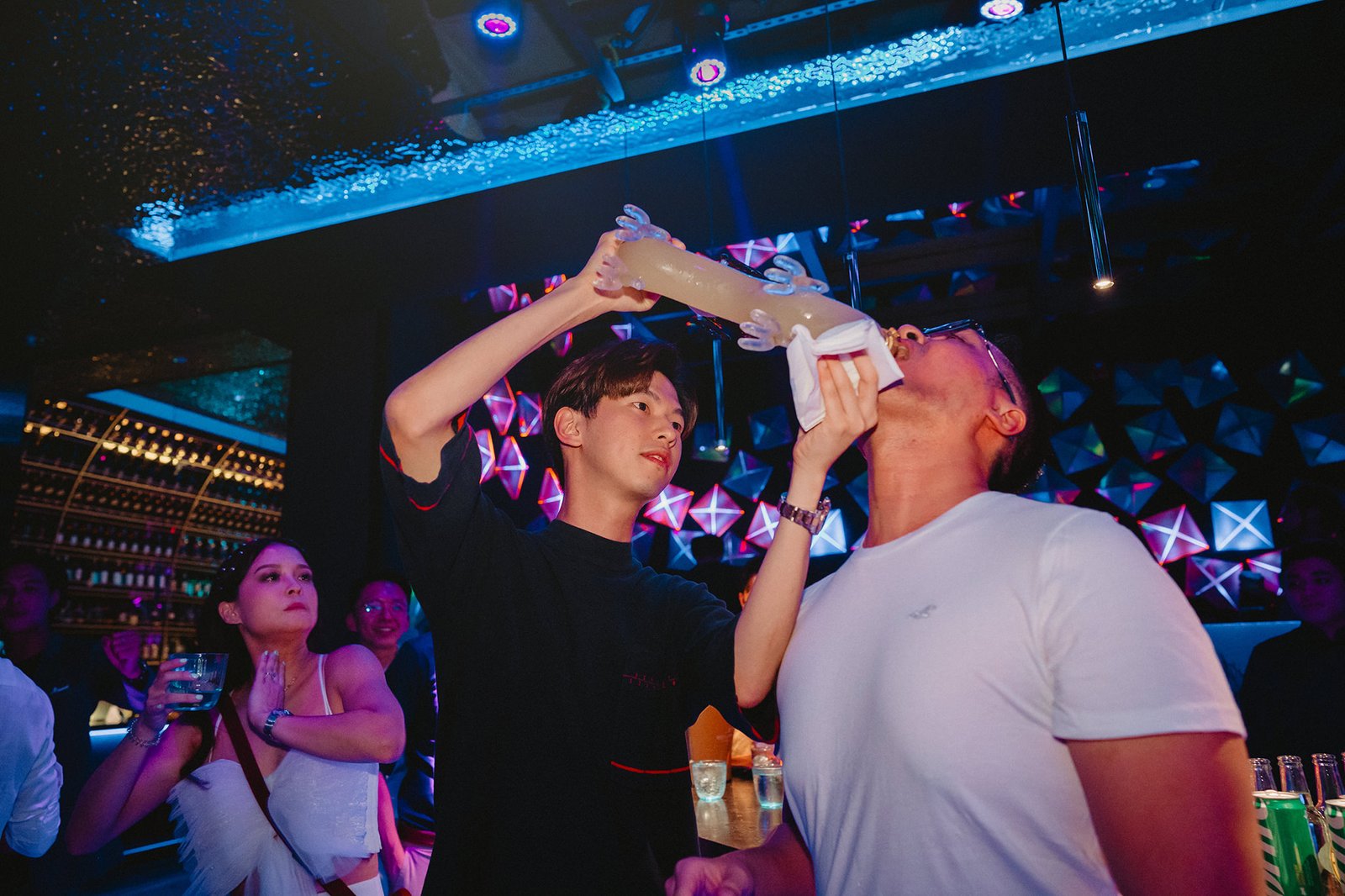 Capella Singapore wedding: Guests share a drink from a large tube at a party.