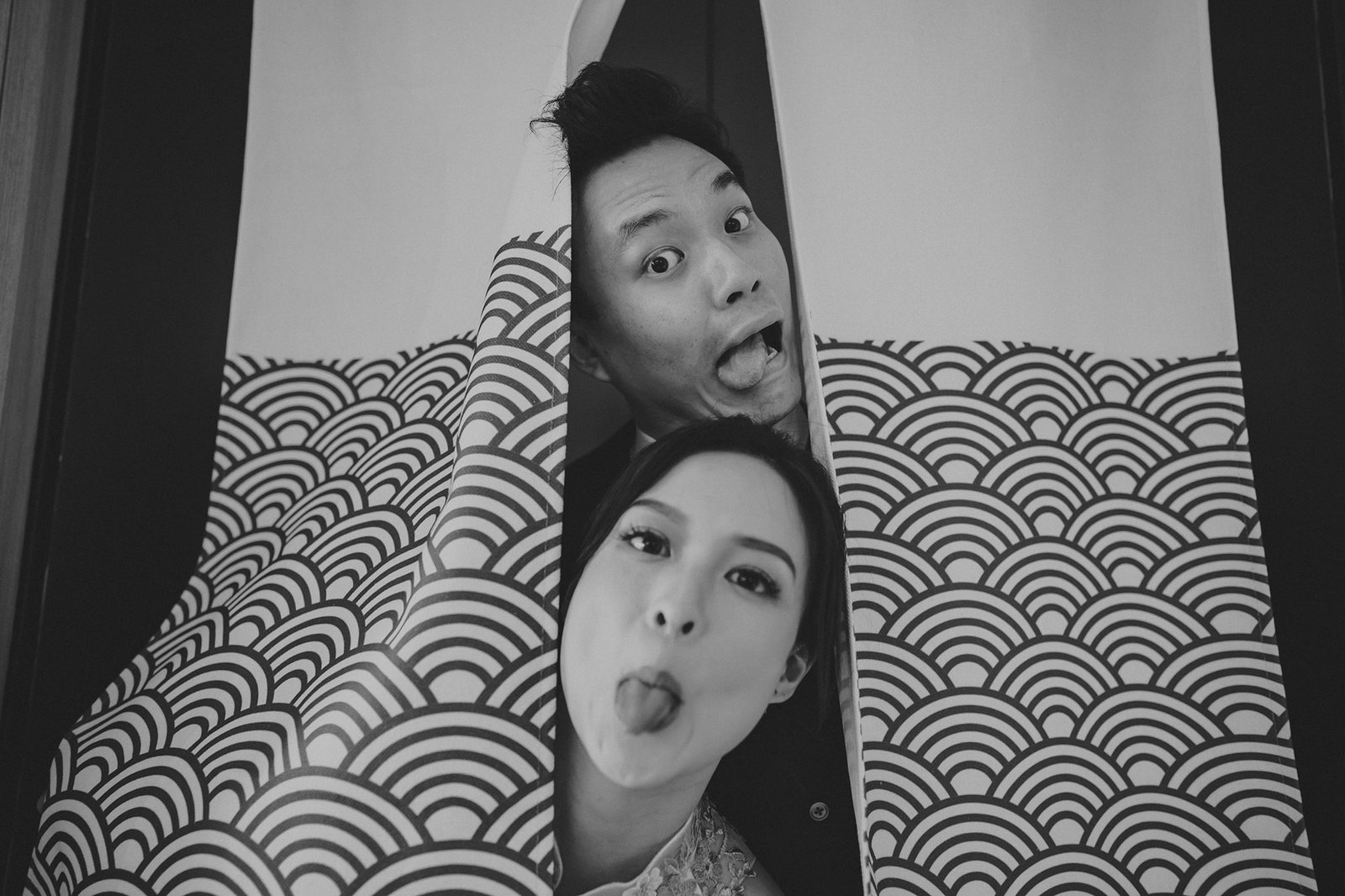 Han and Ming playfully peek through curtains at their Capella Singapore wedding.