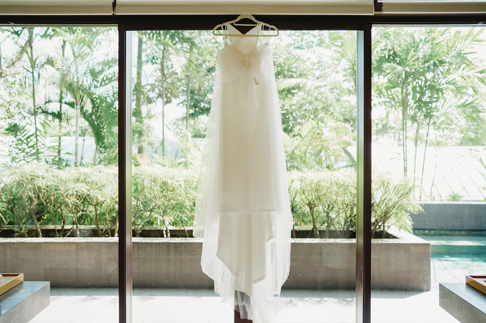 White wedding dress hanging in front of lush greenery at Capella Singapore