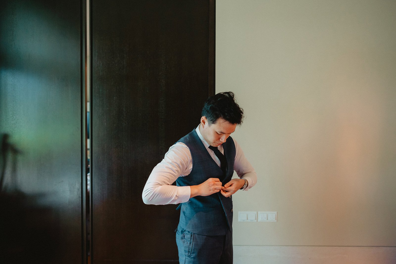 Groom in a blue suit vest getting ready for a Capella Singapore wedding.
