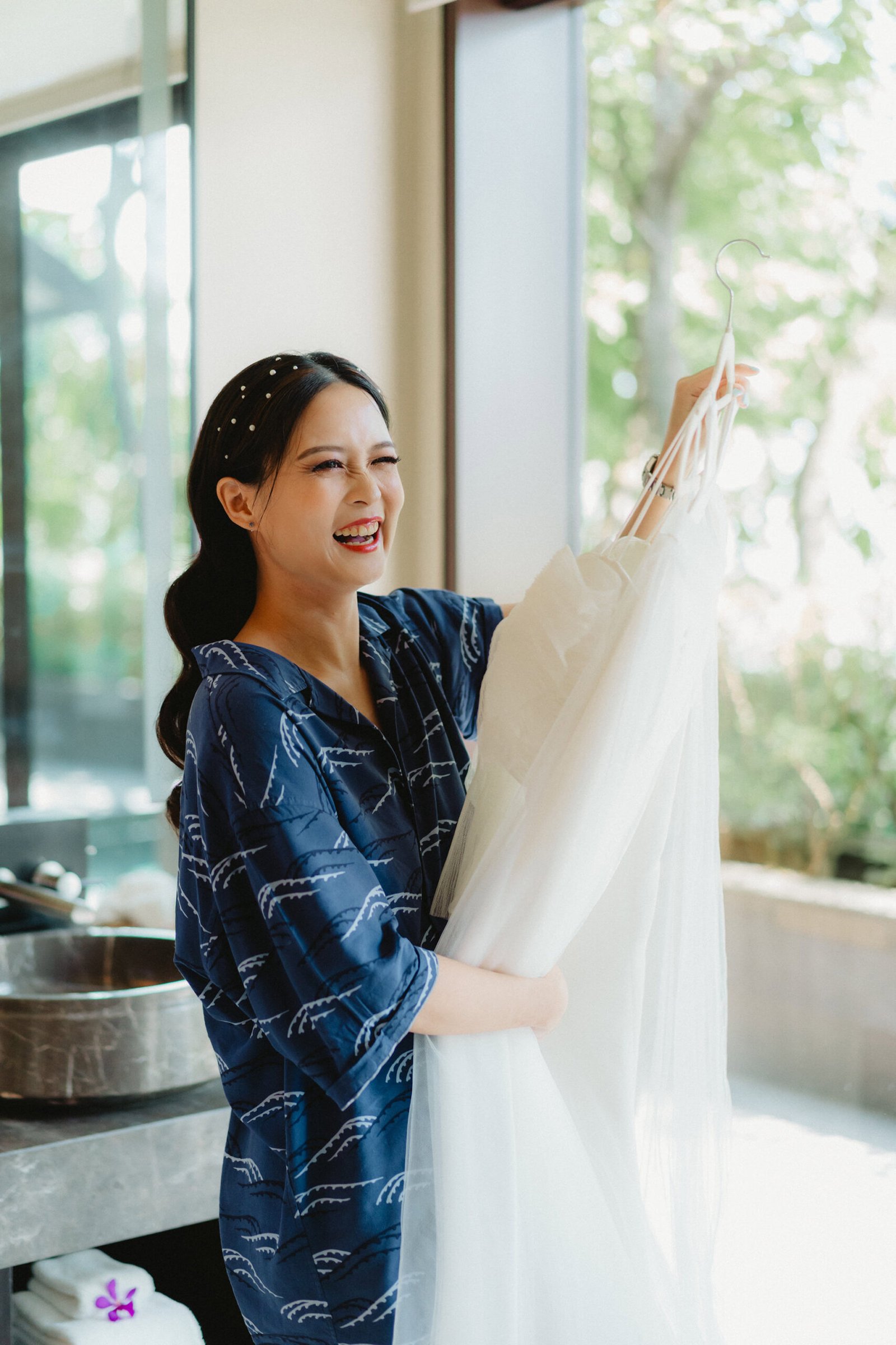 Bride in robe holds wedding dress at Capella Singapore wedding
