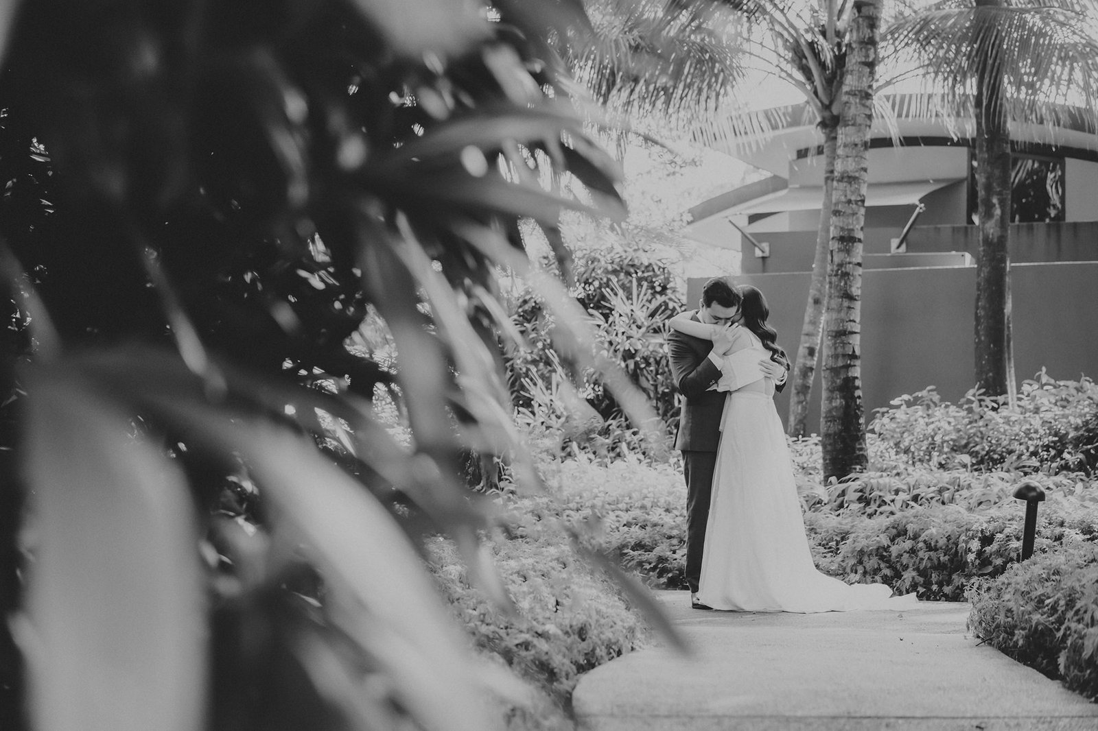 Han and Ming embrace at their Capella Singapore wedding, surrounded by lush greenery.