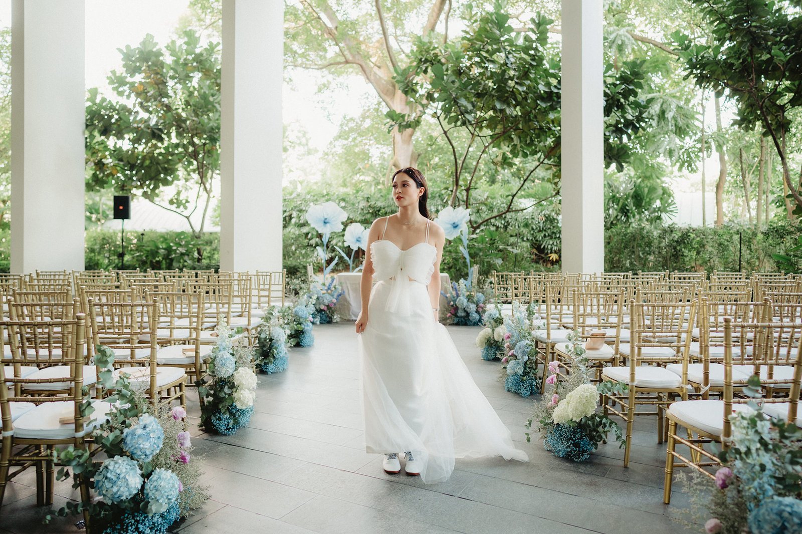 Bride in white dress at Capella Singapore wedding ceremony, surrounded by floral decor