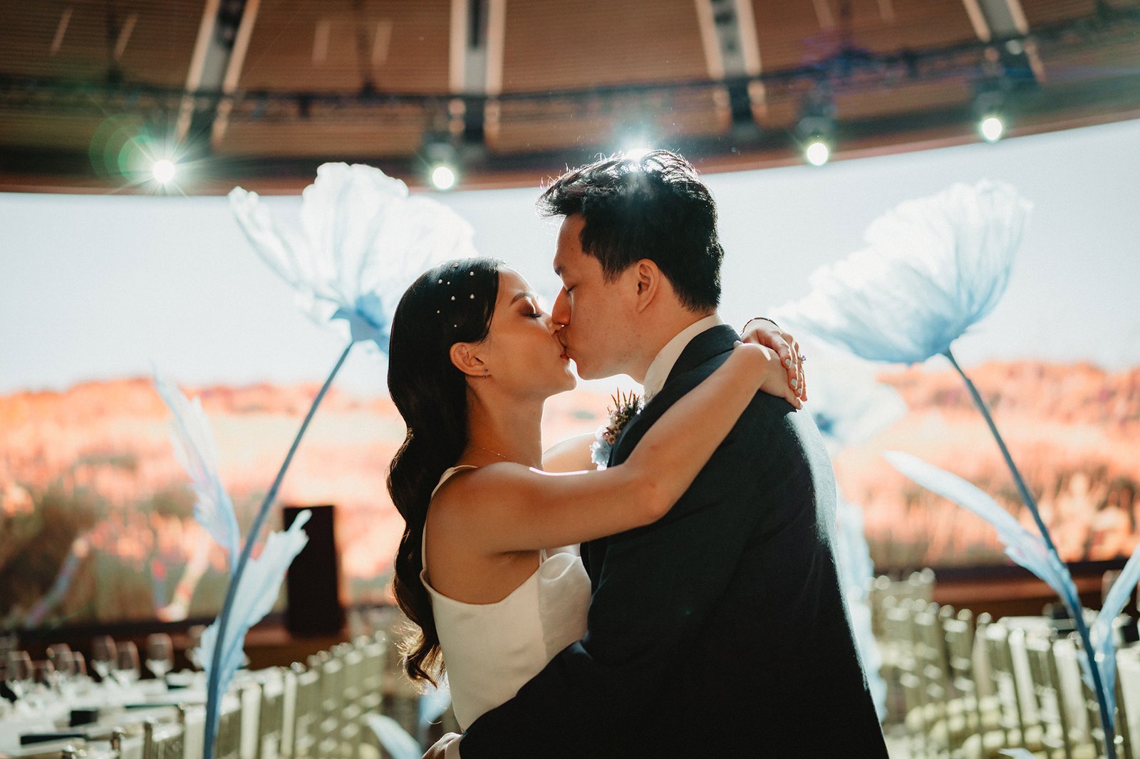 Han and Ming kiss at their Capella Singapore wedding, surrounded by whimsical decor.