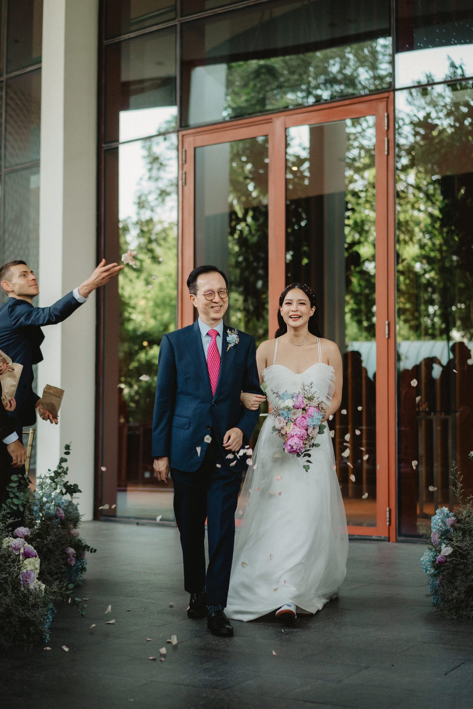 Newlyweds Han and Ming exit their Capella Singapore wedding as guests toss petals.