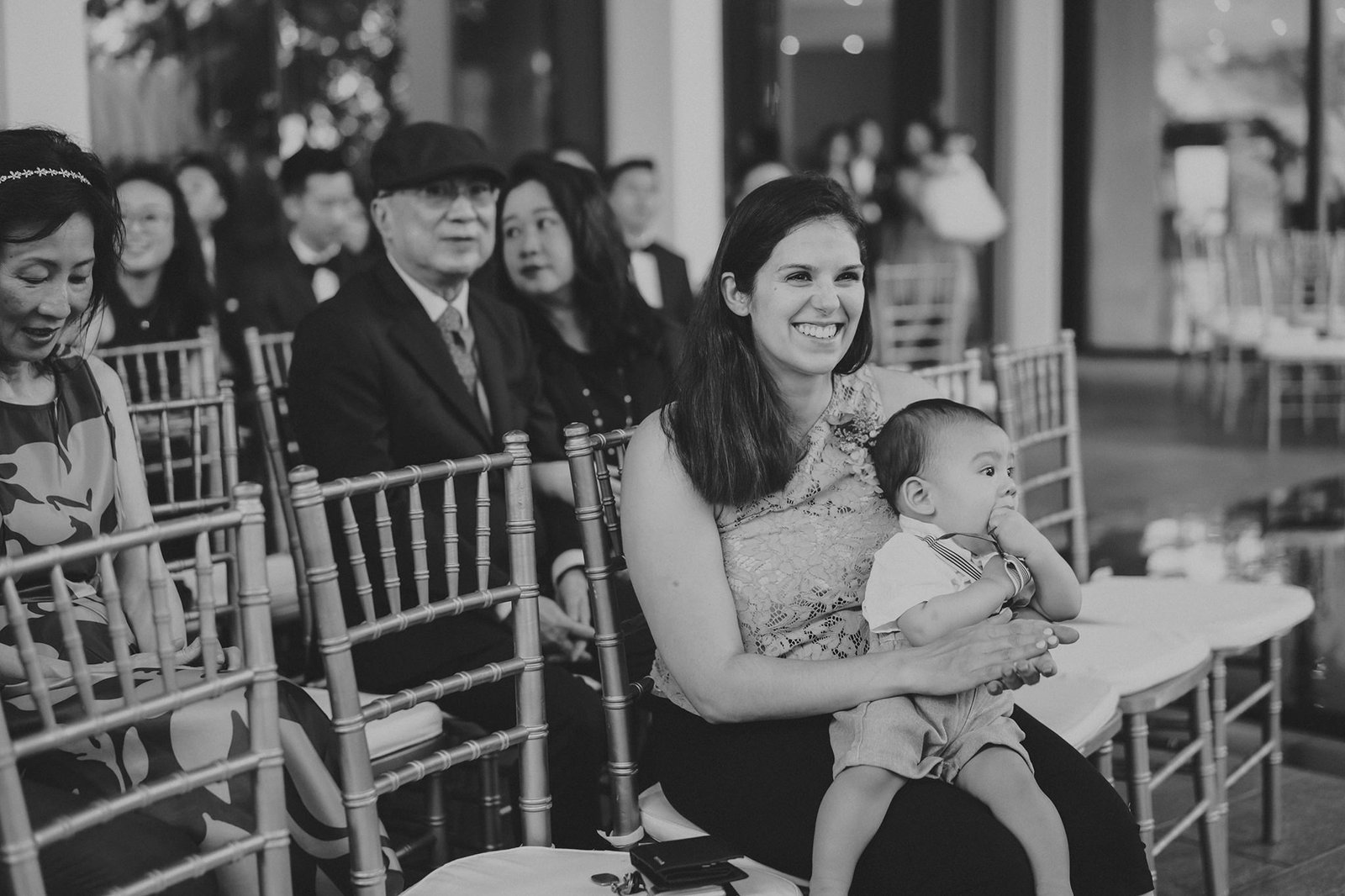 Happy mother smiles holding baby at Capella Singapore wedding
