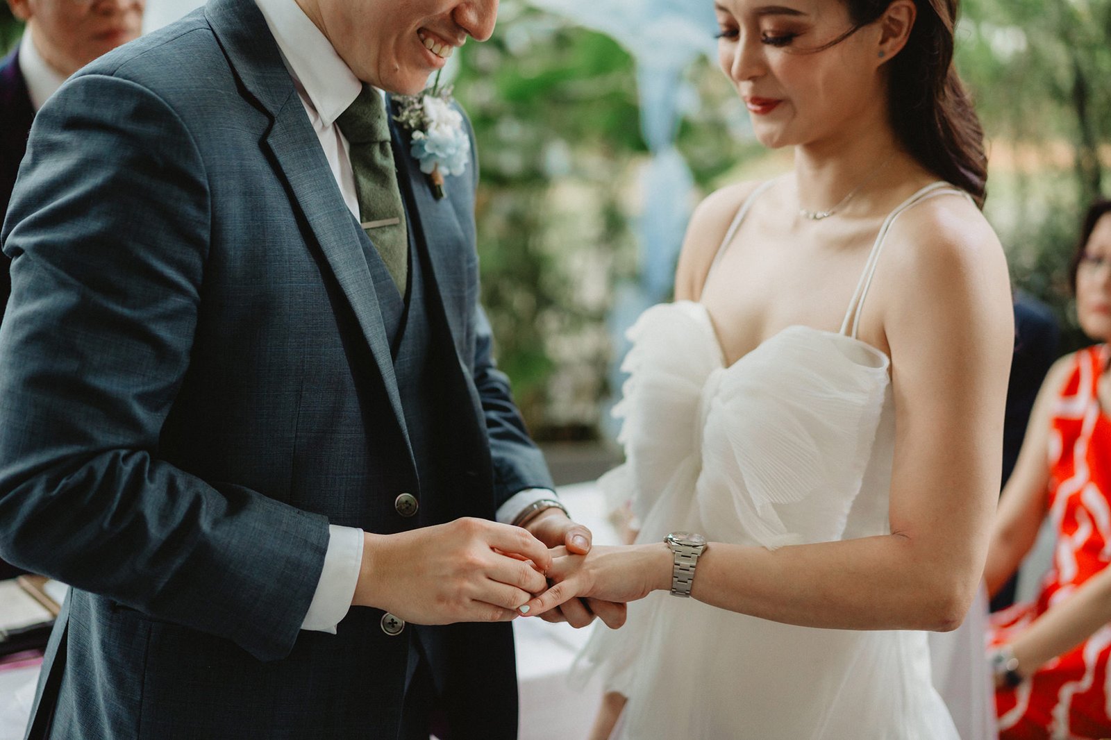 Groom places ring on bride's finger at Capella Singapore wedding ceremony