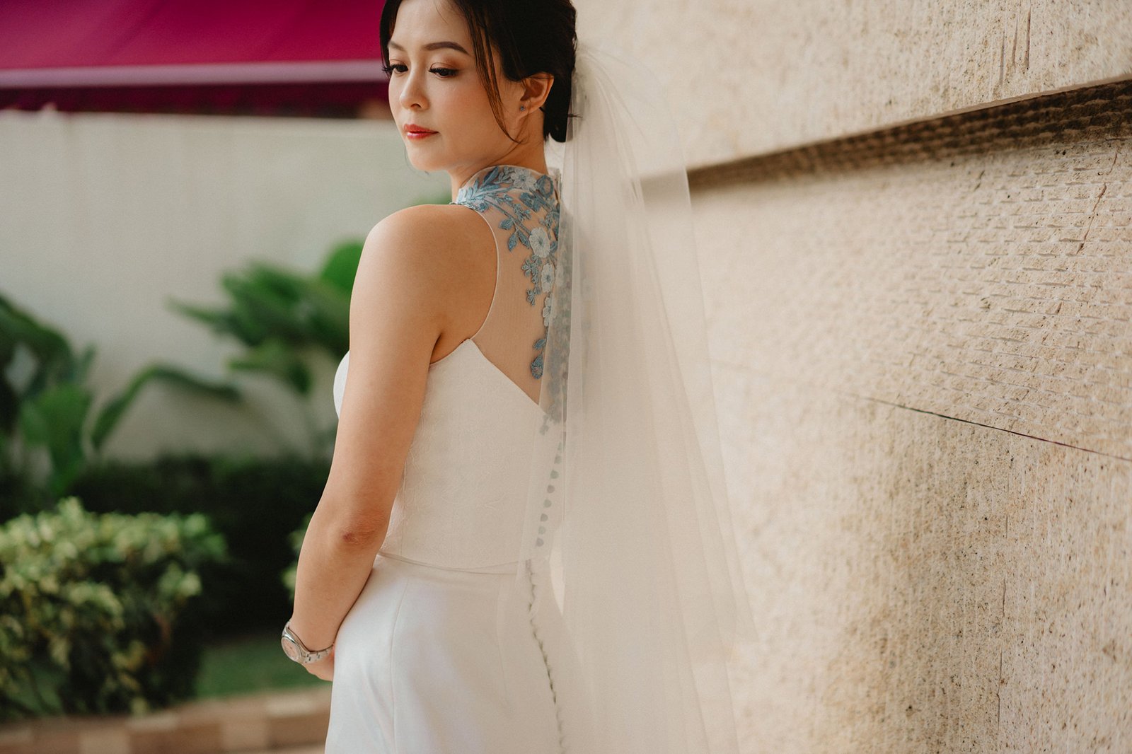Bride in a white gown with intricate blue floral detail on the back at a Capella Singapore wedding.